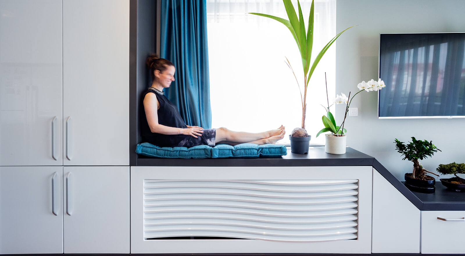 Woman sitting comfortably in a window nook of a contemporary interior.
