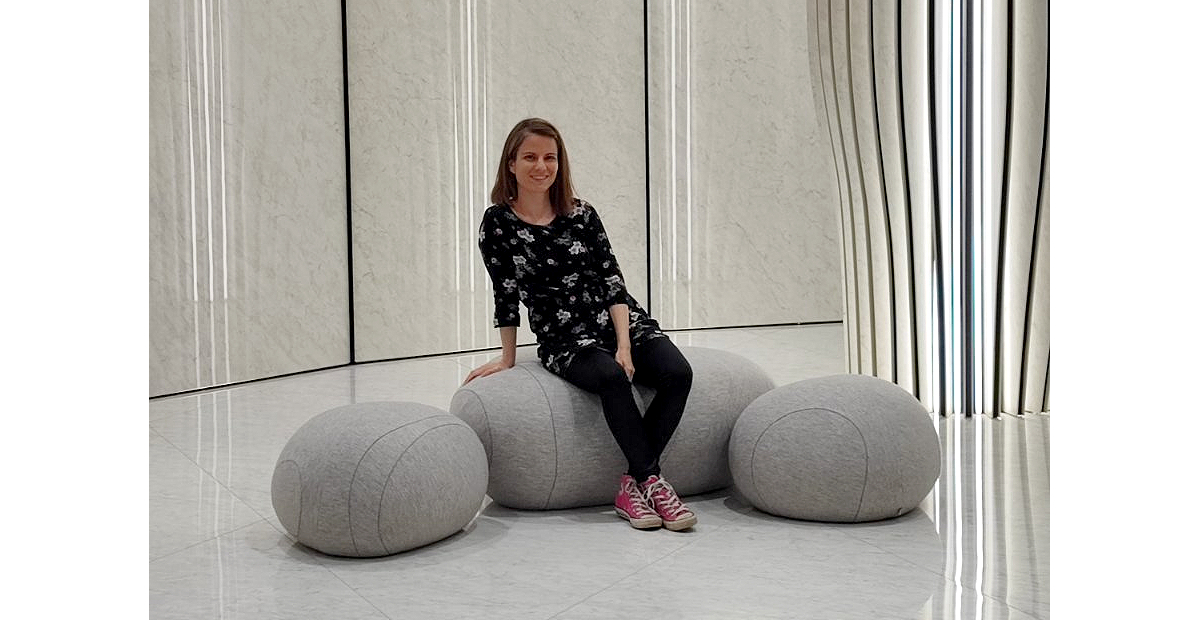 Woman sitting on a gray, comfortable modern pouf chair. 