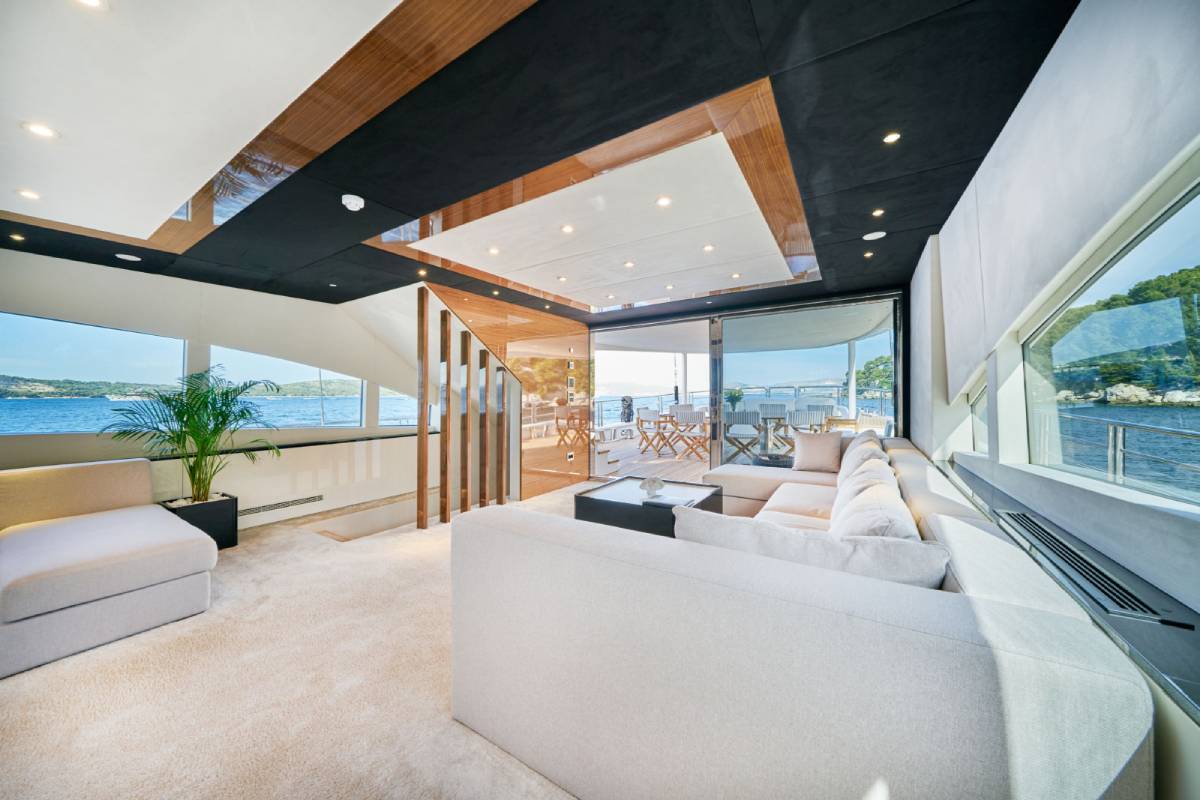 Bright salon of a luxury yacht with cream sofas and warm wooden details on the ceiling