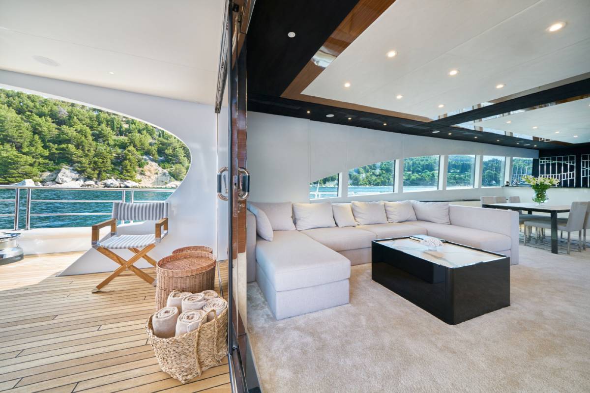 Bright salon of a luxury yacht with cream sofas and warm wooden details on the ceiling