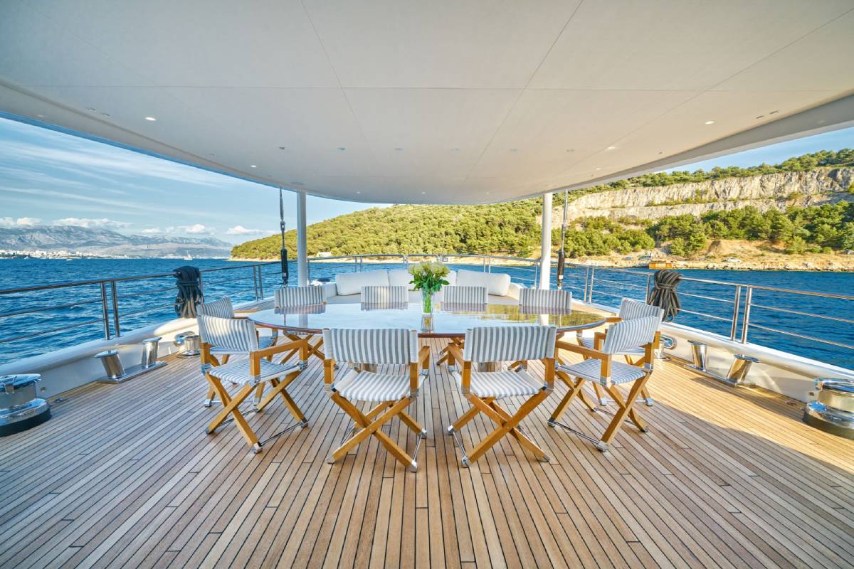 The aft deck of a luxury yacht with outdoor dining and panoramic sea views
