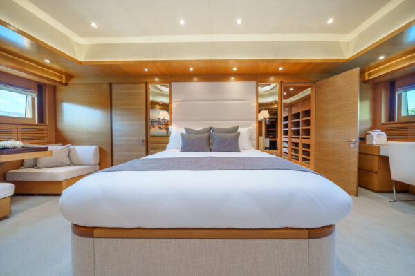 The master cabin of the Silent World yacht with a large bed and warm wooden panelling