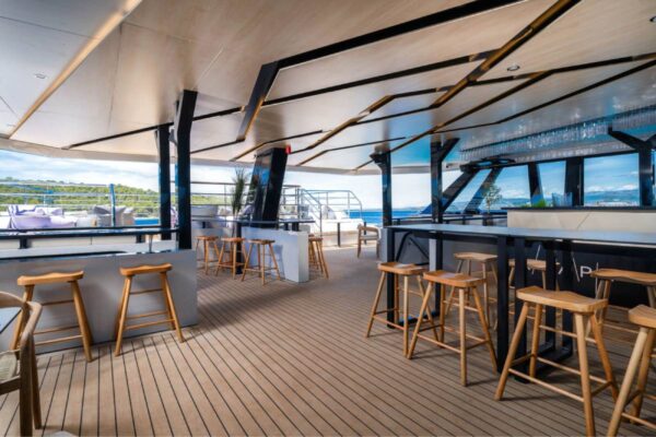 Covered catamaran deck bar with wooden bar stools
