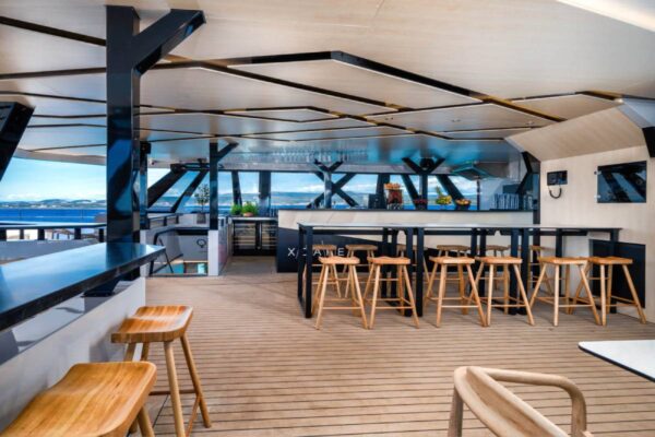 Covered catamaran deck bar with wooden bar stools